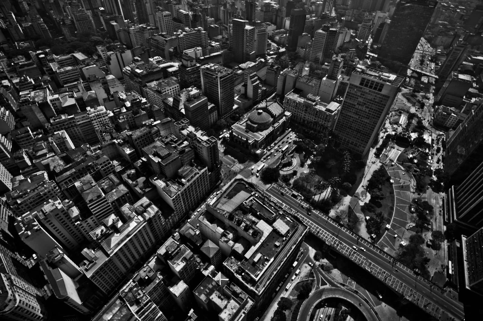 aerial view of a dense city centre with high‑rise buildings, roads and public squares.