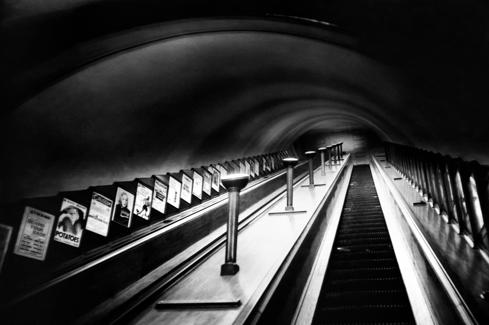  An escalator on London Underground with posters on show at the side.