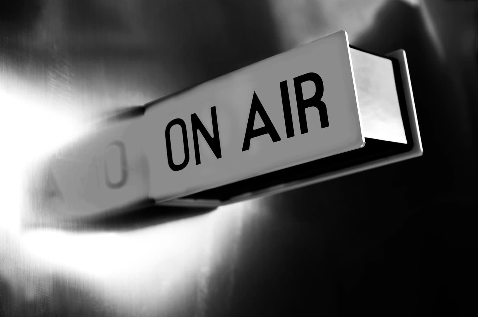 Illuminated ON AIR sign in black and white, commonly used in broadcasting studios during live recording.