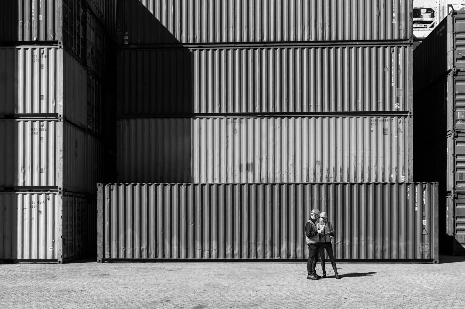 Two workers in discussion against cargo containers