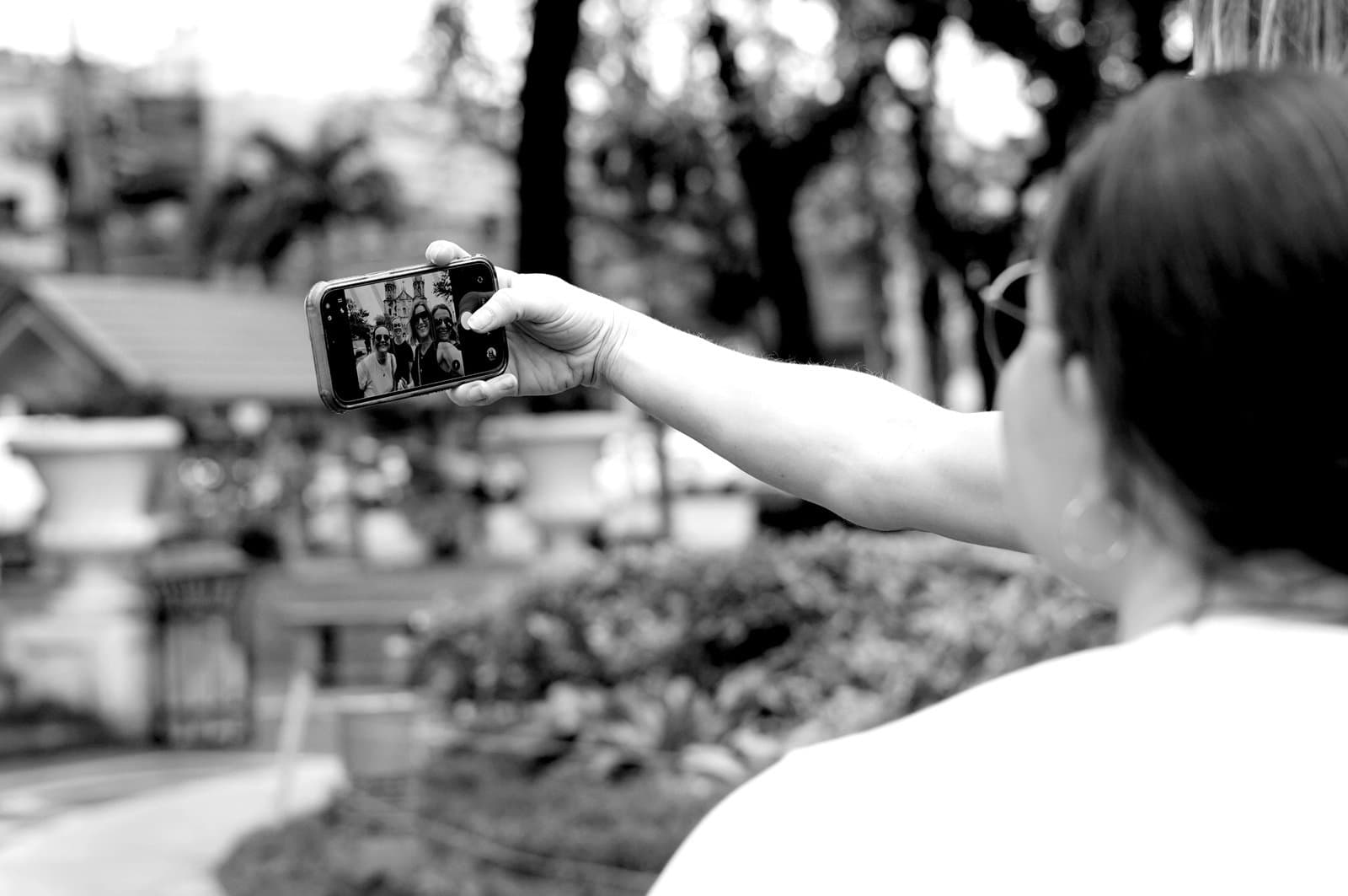 A hand extending to take a selfie image of a group of people